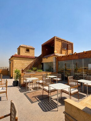 A rooftop patio with outdoor seating, a wooden staircase, and a view of the city. - Gardenia pyramids Palace (Giza)