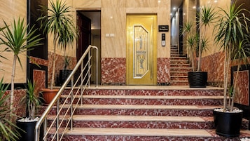 A reception area with marble steps, a golden door, and potted plants.