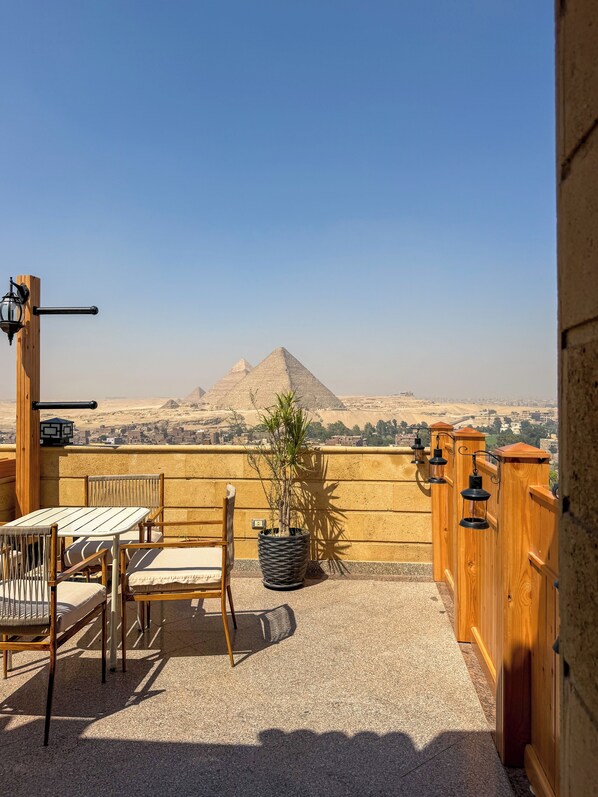 Una terraza con vistas a pirámides, muebles de madera y una planta en maceta.