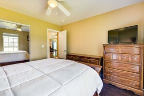 A bedroom with a bed, a dresser, a television, and a ceiling fan.