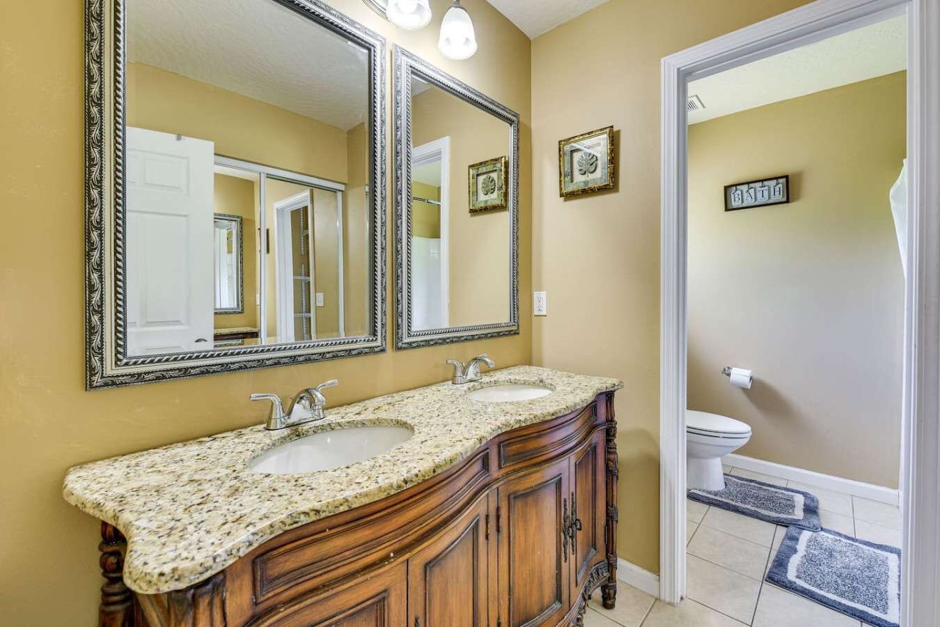 A bathroom with two sinks, a large mirror, and a toilet.