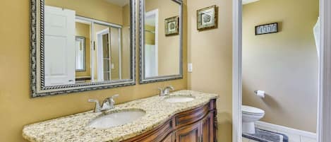 A bathroom with two sinks, a large mirror, and a toilet.