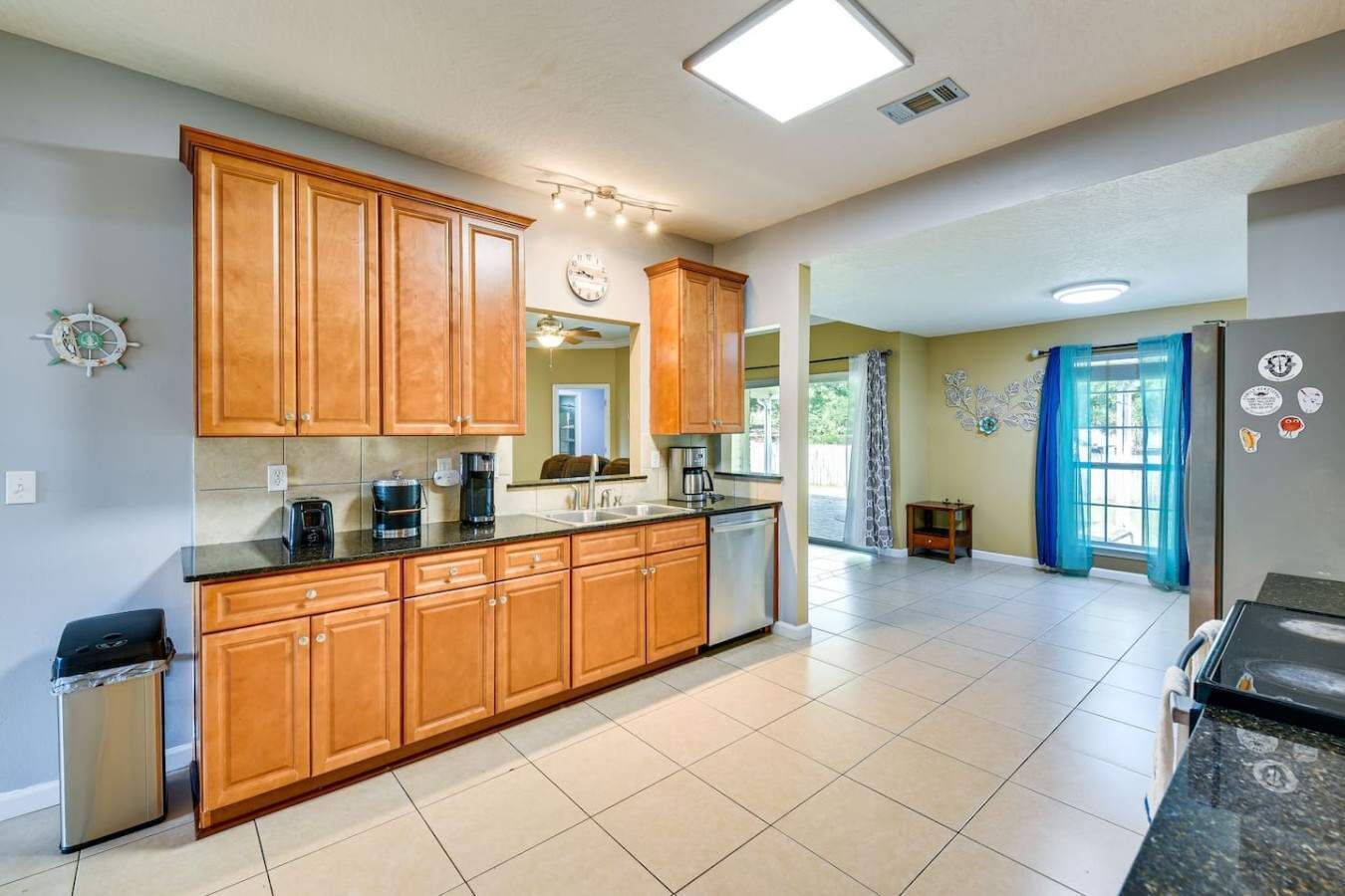 A kitchen with wooden cabinets, a stainless steel refrigerator, and a tiled floor.