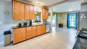 A kitchen with wooden cabinets, a stainless steel refrigerator, and a tiled floor. - 6BR Family Home Near Twin Hills Fire Pit (Crestview)