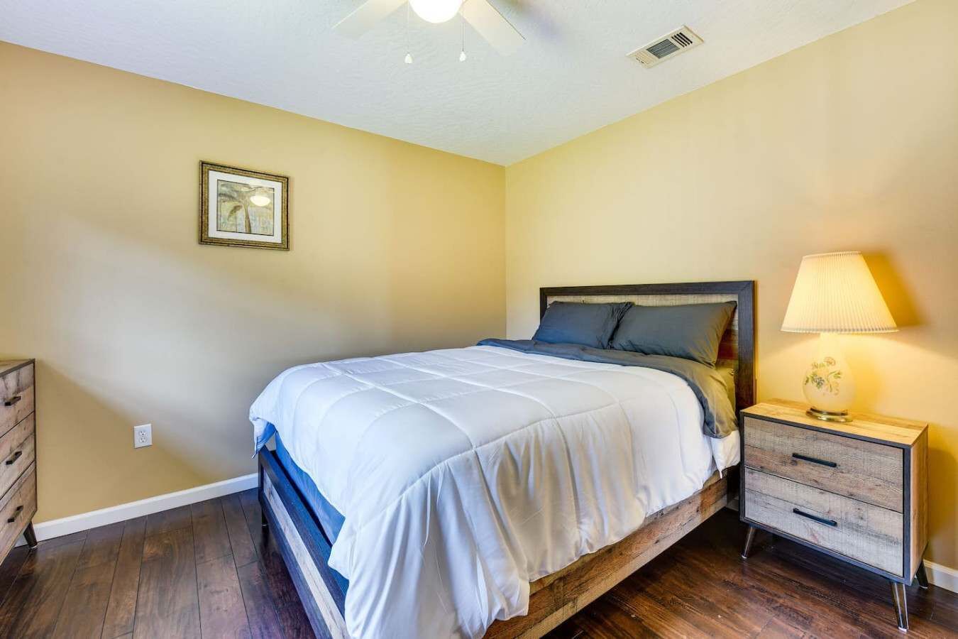 A bedroom with a bed, nightstand, dresser, and a ceiling fan.