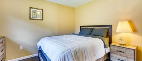 A bedroom with a bed, nightstand, dresser, and a ceiling fan.