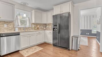 A modern kitchen with white cabinets, a stainless steel refrigerator, and a dishwasher.