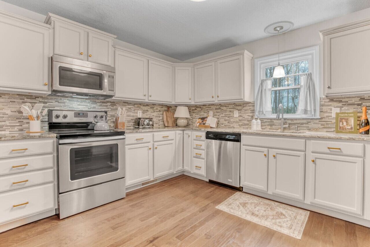 A kitchen with white cabinets, stainless steel appliances, and a tiled backsplash.