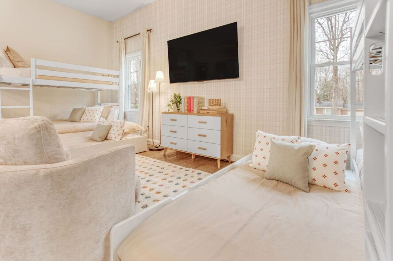 Quarto com beliches, televisão de tela plana, cômoda e janela com vista.