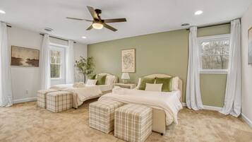 A bedroom with two beds, a ceiling fan, and a large window with curtains.