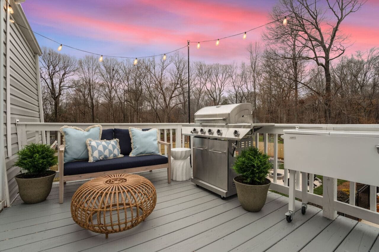 Eine Terrasse mit Grill, Sitzgelegenheiten und Lichterketten.