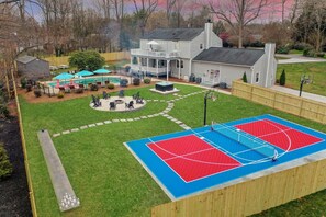 A residential property with a basketball court, a covered patio, and a large house with a porch. - Greensboro Getaway Villa (Greensboro)