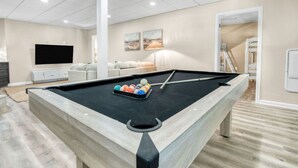 A pool table in a room with a flat-screen TV, a sofa, and a lamp. - Arlington Oasis 7 Br (Jamestown)