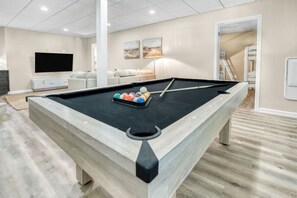 A pool table in a room with a flat-screen TV, a sofa, and a lamp. - Arlington Oasis 7 Br (Jamestown)