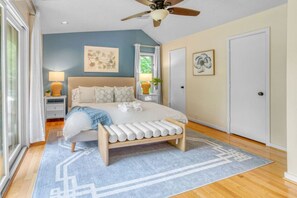 A bedroom with a bed, bedside tables, a ceiling fan, and artwork on the walls. - Arlington Oasis 7 Br (Jamestown)