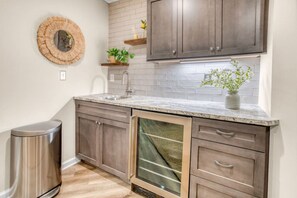 A kitchen with dark wooden cabinets, a granite countertop, a stainless steel trash can, and a built-in dishwasher. - Arlington Oasis 7 Br (Jamestown)