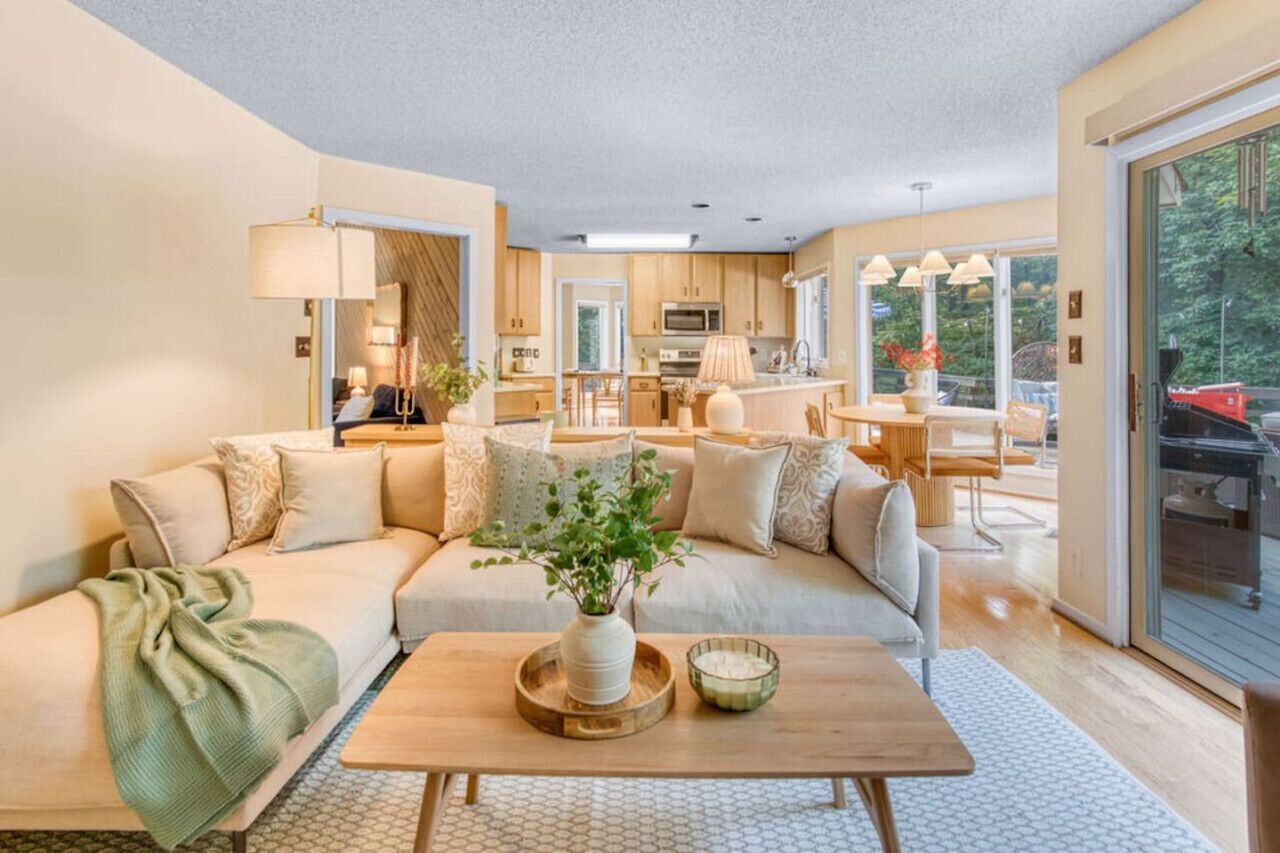 A modern living room with a sofa, coffee table, and a dining area.