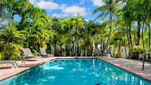 A swimming pool surrounded by palm trees and lounge chairs. - Tropical Villa Retreat Pool & Hot Tub (Key Largo)