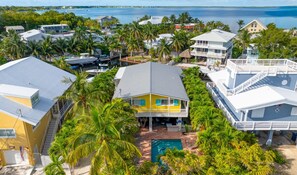 Une propriété située sur la côte, avec un bâtiment jaune au centre, une piscine et des palmiers tout autour.