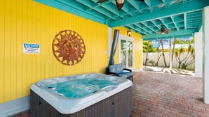 A hot tub under a covered area with a ceiling fan, a notice sign, and a decorative sun wheel. - Tropical Villa Retreat Pool & Hot Tub (Key Largo)