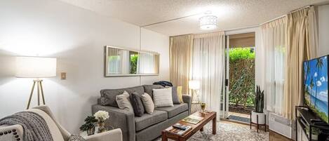 A living room with a sofa, armchair, coffee table, and a television.
