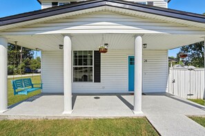 A covered porch with a blue door, white columns, and a hanging planter. - Renovated 6BR Near Grand Lake Fire Pit & Games (Grove)