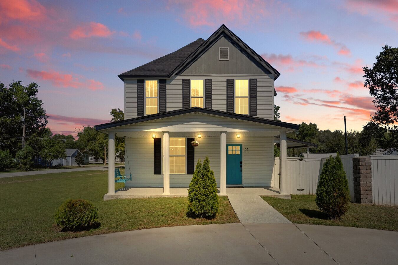 A two-story house with a porch, a blue door, and a number 211 on the front.