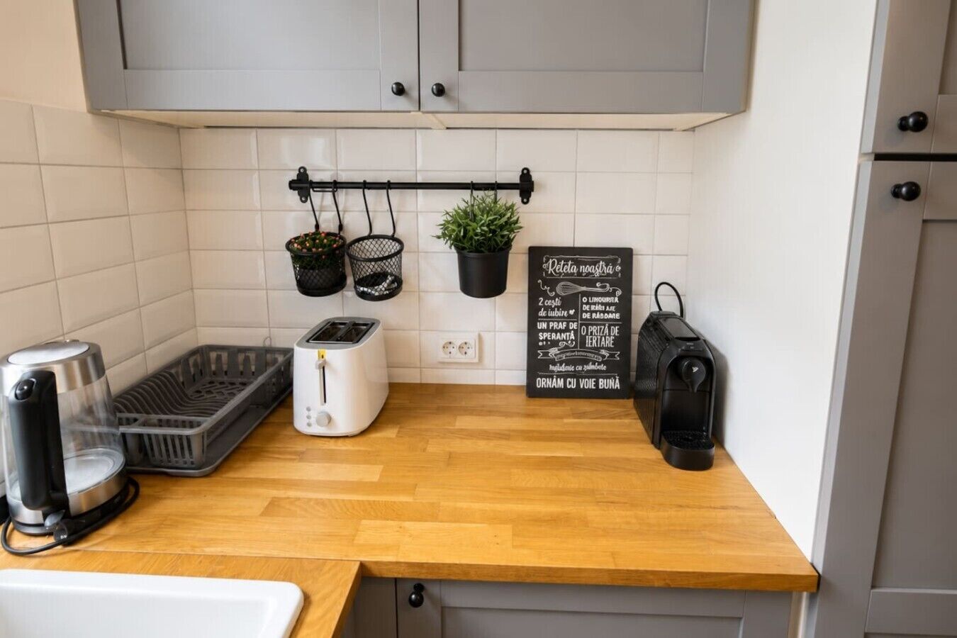 Een keuken met een broodrooster, koffiezetapparaat, een mand en een hangplant.