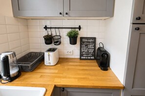 Eine Küche mit einem Toaster, einer Kaffeemaschine, einem Korb und einer hängenden Pflanze.