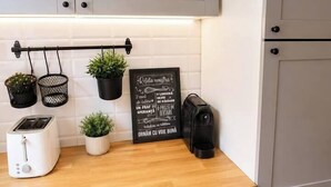 A kitchen with grey cabinets, a wooden countertop, a toaster, a coffee maker, and potted plants. - Elegant Boutique Apartment with Luxury Bedroom (Bucharest)