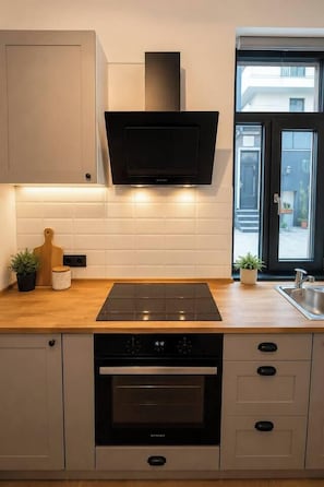 A modern kitchen with a built-in oven, a microwave, and a black range hood. - Elegant Boutique Apartment with Luxury Bedroom (Bucharest)