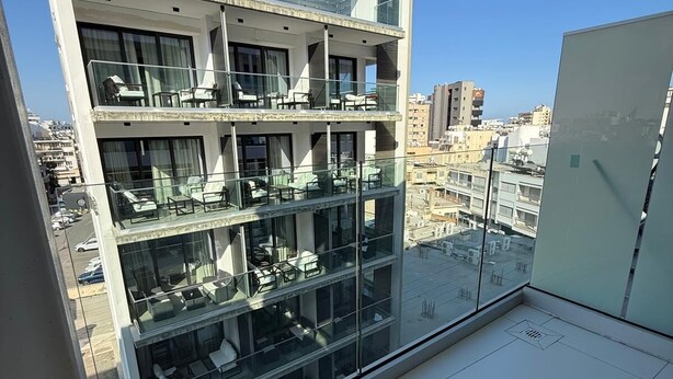 Un immeuble moderne à plusieurs étages, doté de balcons, de grandes fenêtres et offrant une vue sur le paysage urbain.