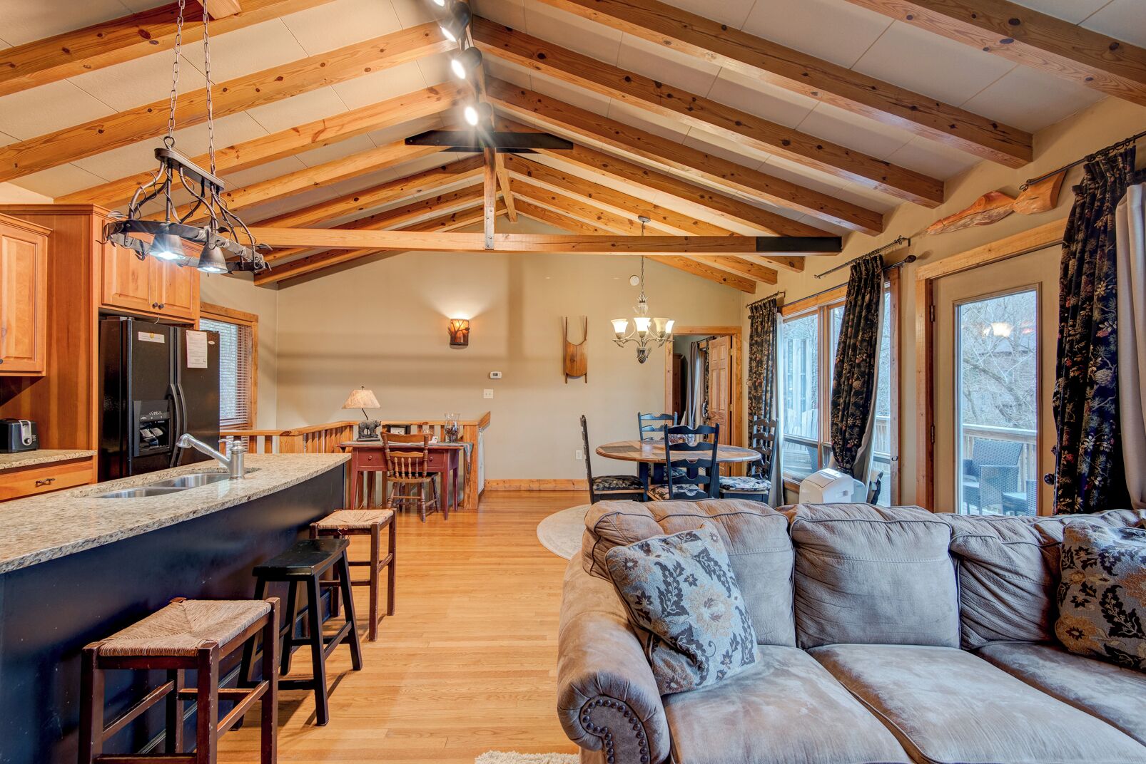 Un salón amplio con un sofá grande y una zona de comedor con mobiliario de madera.