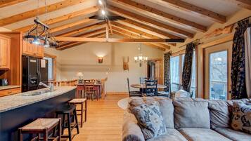 Un salón amplio con un sofá grande y una zona de comedor con mobiliario de madera.