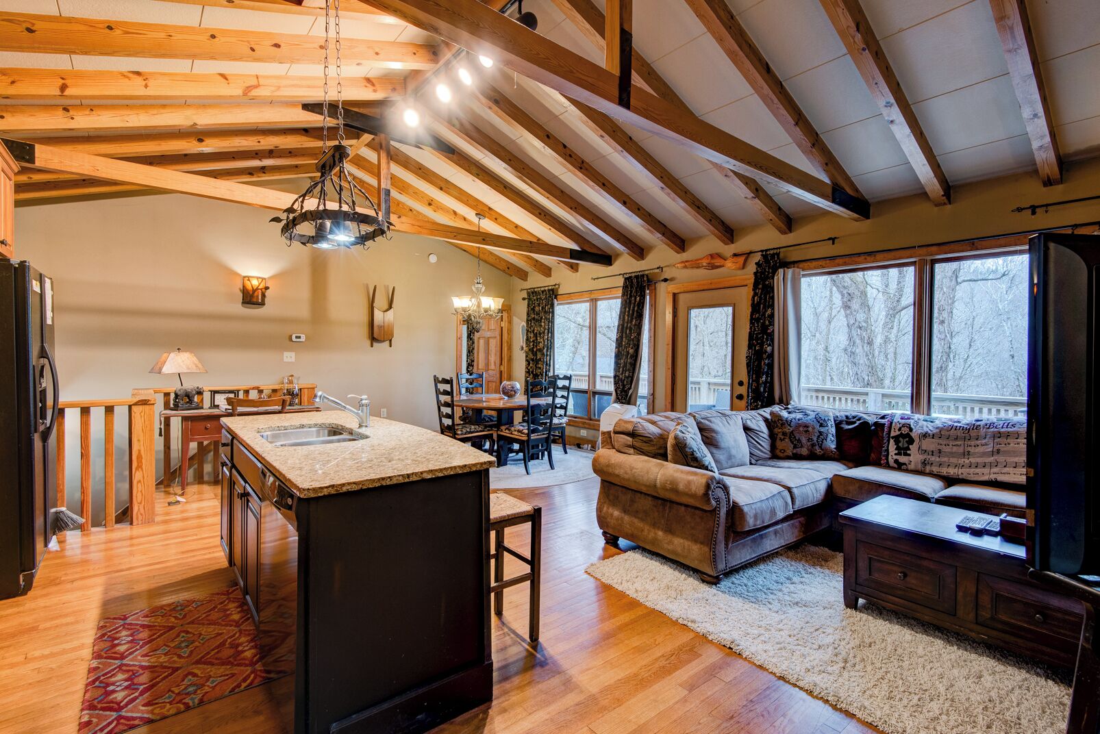 A spacious living area with a wooden ceiling, a kitchen with a granite countertop, and a cozy seating area with a sofa and a coffee table.