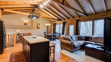 A spacious living area with a wooden ceiling, a kitchen with a granite countertop, and a cozy seating area with a sofa and a coffee table.