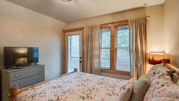 Un dormitorio con cama, televisor en una cómoda y ventana con cortinas.