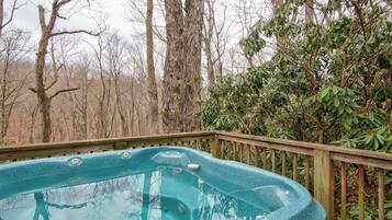 Un jacuzzi en una terraza de madera rodeado de árboles.