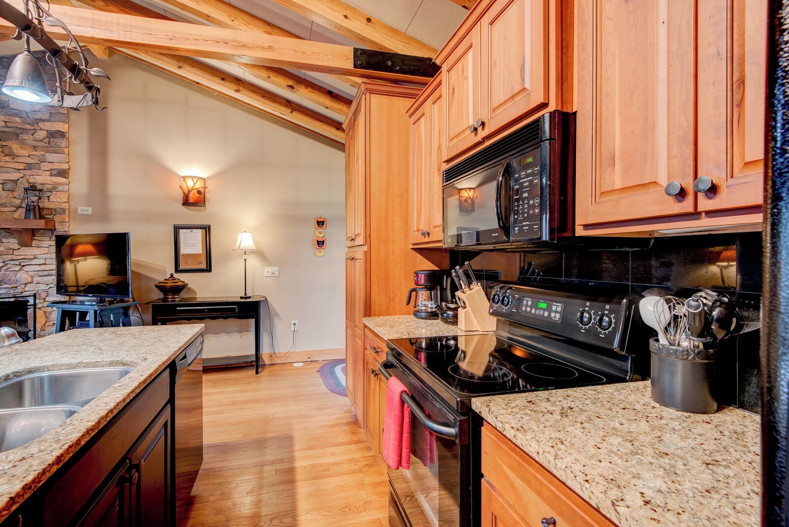 A kitchen with wooden cabinets, a black stove, and granite countertops.