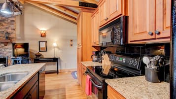 A kitchen with wooden cabinets, a black stove, and granite countertops.