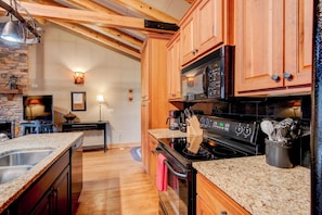 A kitchen with wooden cabinets, a black stove, and granite countertops. - Appalachian Retreat (Blowing Rock)