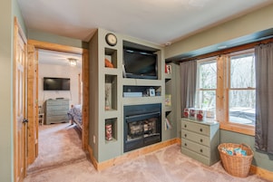 Una sala de estar acogedora con chimenea, televisor y ventana con cortinas.