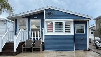 Ein eingeschossiges Haus mit Veranda, einem Kompass an der Wand und einem Schild mit der Nummer 447.