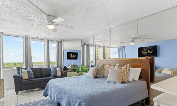 Ein Hotelzimmer mit Bett, Sofa, Schreibtisch und Blick auf die Stadt.