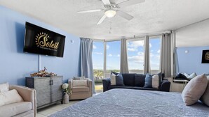 A bedroom with a large bed, a sofa, a TV, and a view of the sky. - Top of the Gulf 816 (Panama City Beach)