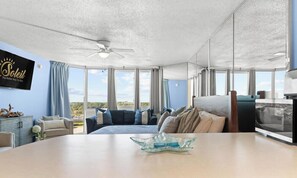 Ein modernes Hotelzimmer mit einem großen Bett, einem Esstisch, einem Fernseher und Blick auf die Stadt.