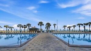 A swimming pool area with hexagonal tiles, palm trees, and a small pavilion. - Summit 625 (Panama City Beach)
