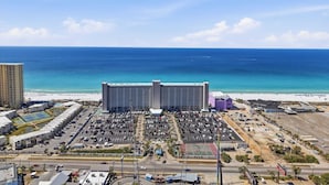A large hotel with a view of the ocean, parking lots, and a tennis court. - Summit 625 (Panama City Beach)