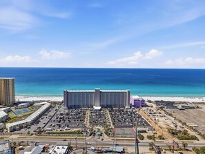 A large hotel with a view of the ocean, parking lots, and a tennis court. - Summit 625 (Panama City Beach)