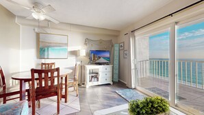 A balcony with a view of the ocean, a dining area with chairs and a table, a television on a cabinet, and a 'WELCOME' sign. - Summit 1013 (Panama City Beach)